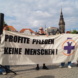 Personen halten ein Banner mit der Aufschrift "Profite pflegen keine Menschen!" hoch.