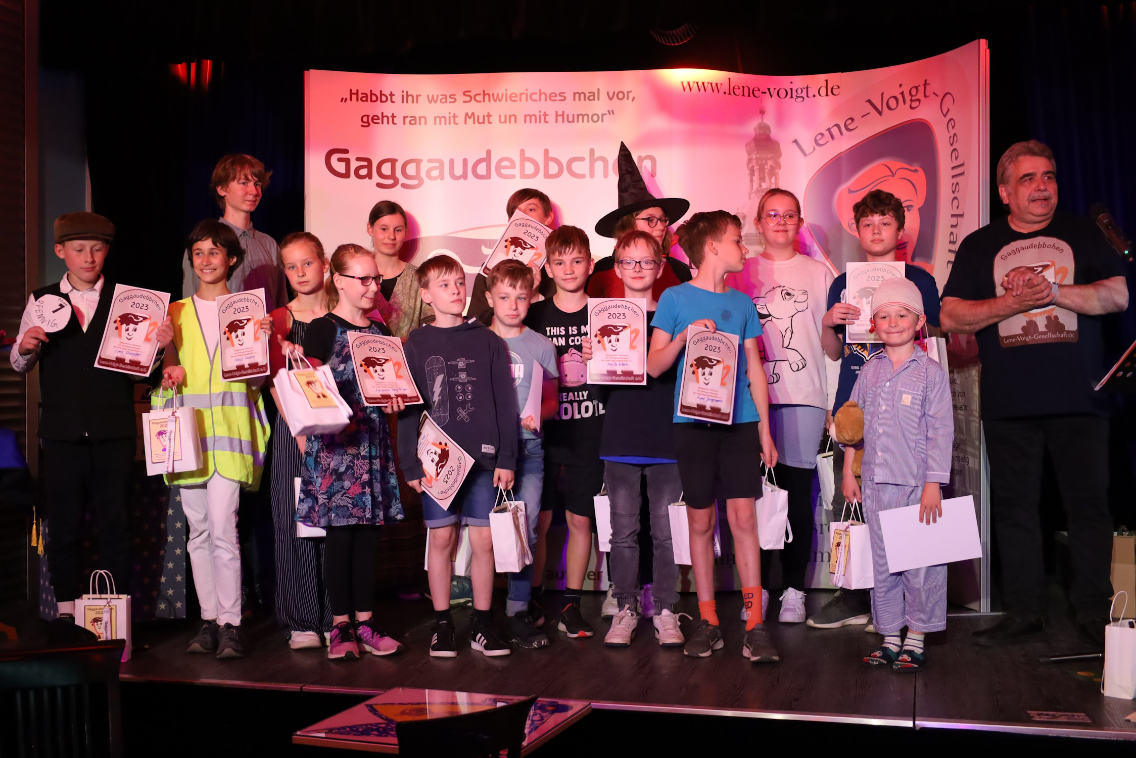 Zu sehen sind alle Teilnehmerinnen und Teilnehmer am Gaggaudebbchen-Wettbewerb 2023 mit Klaus Peterman auf der Bühne des Kabaretts Sanftwut. Foto: Ralf Julke