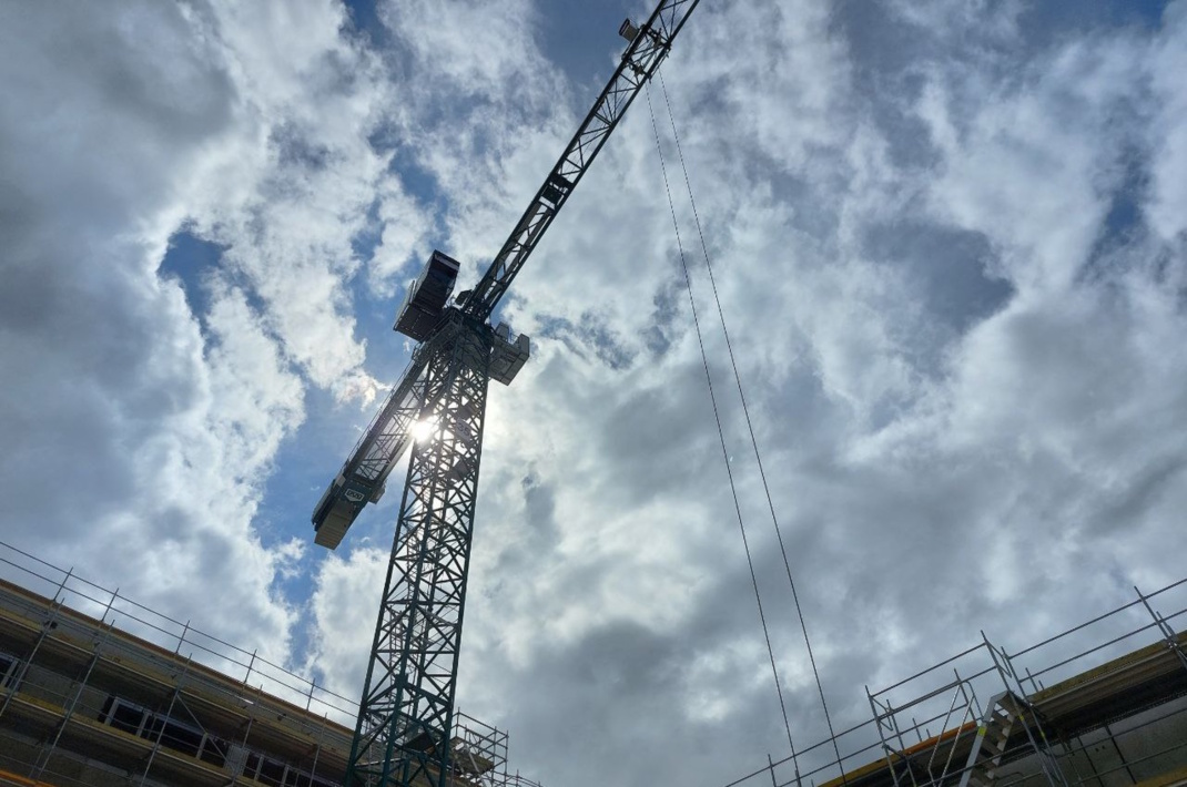 Kran von unten mit Wolken am Himmel.