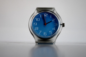 Uhr mit blauem Untergrund und roten Zeigern.