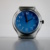 Uhr mit blauem Untergrund und roten Zeigern.