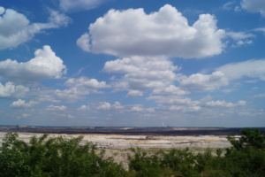 Tagebaulandschaft, blauer Himmel und weiße Wolken.