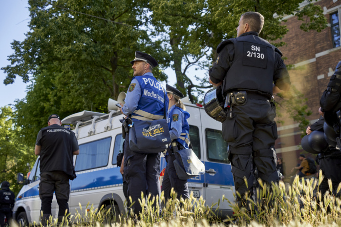 Polizist*innen des Medienteams stehen auf einer Wiese.