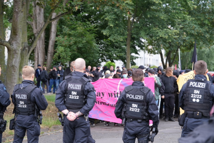 Personen mit Banner, im Vordergrund Polizeibeamte