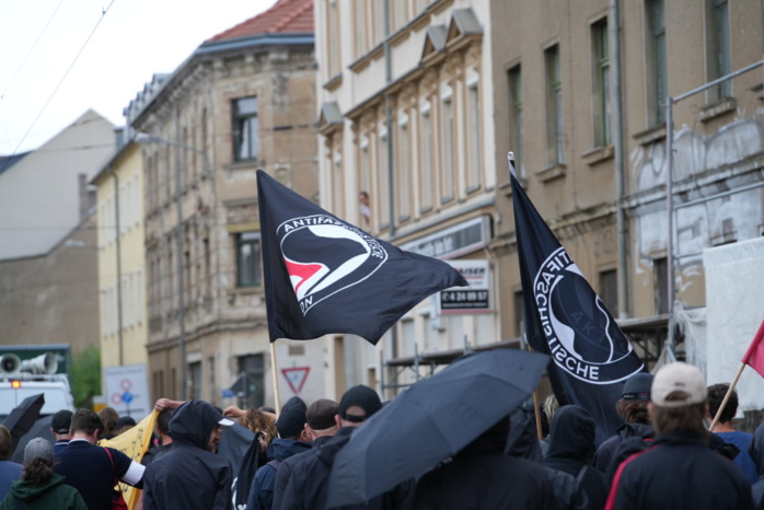 Gruppe von schwarz gekleideten Personen mit Antifa-Fahne