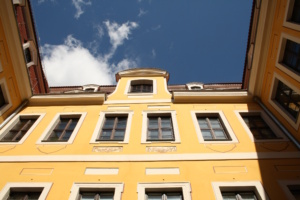 Innenhof, gelbe Hausfassade und Blick gen Himmel.