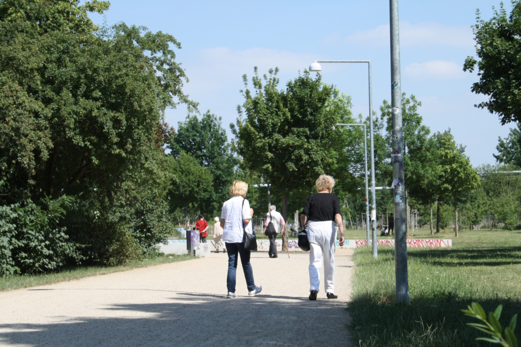 Menschen spazieren auf einem Parkweg.
