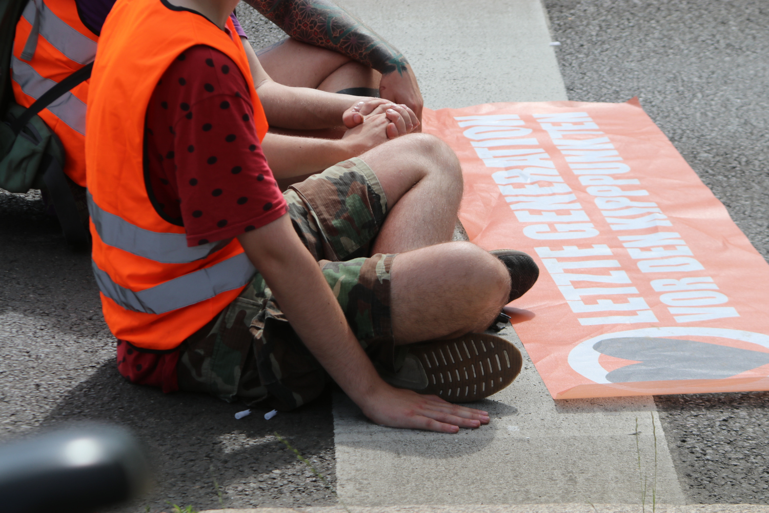 Festgeklebte Aktivisten auf dem Asphalt.