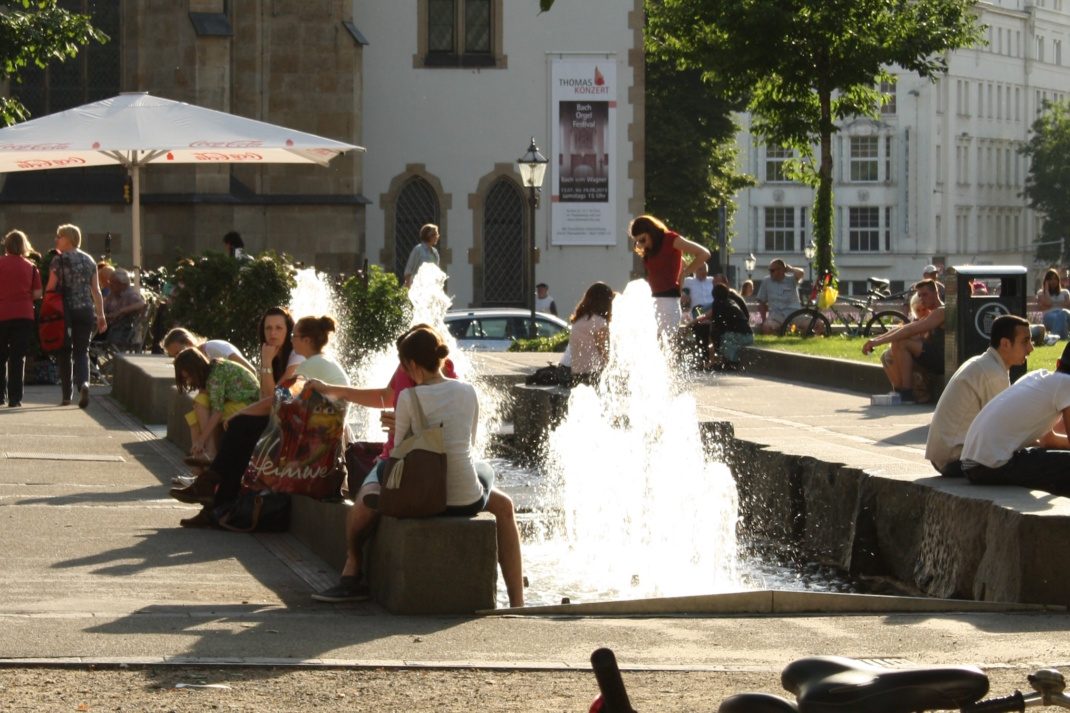 Menschen erfrischen sich am Springbrunnen Thomaswiese.