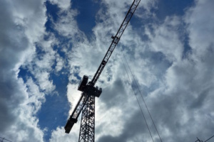 Baukran von unten mit Wolken am Himmel.