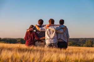 Vier junge Menschen, die Arm in Arm auf einem Feld stehen