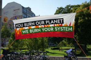 Banner mit der Aufschrift "You burn our planet, we burn your system"