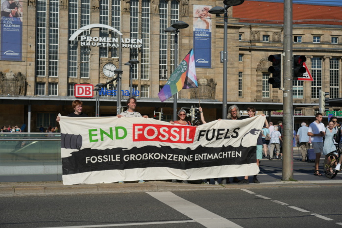 Personengruppe vor dem Leipziger Hauptbahnhof tragen ein Banner