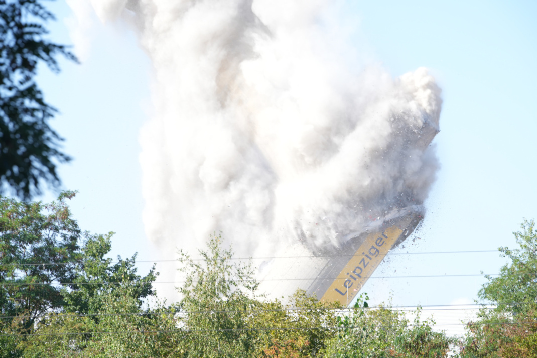 Schornstein während der Sprengung und Staubwolke.