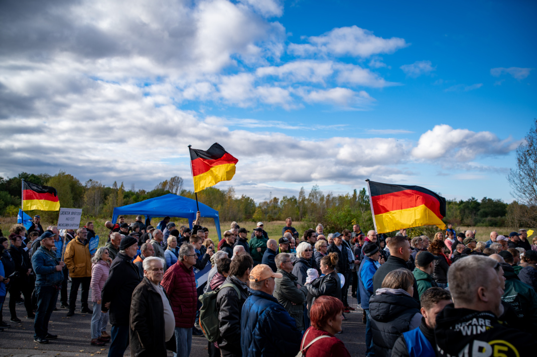 Menschen bei Protestkundgebung der AfD und Gegenprotest, Deutschlandflaggen.