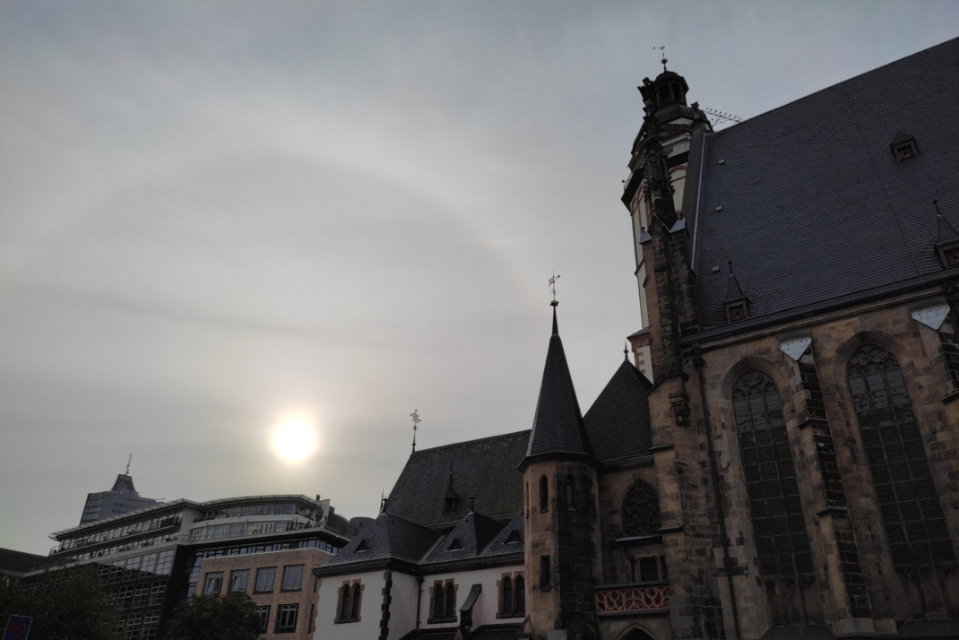 Sonne, Lichtbogen und Kirchengebäude.