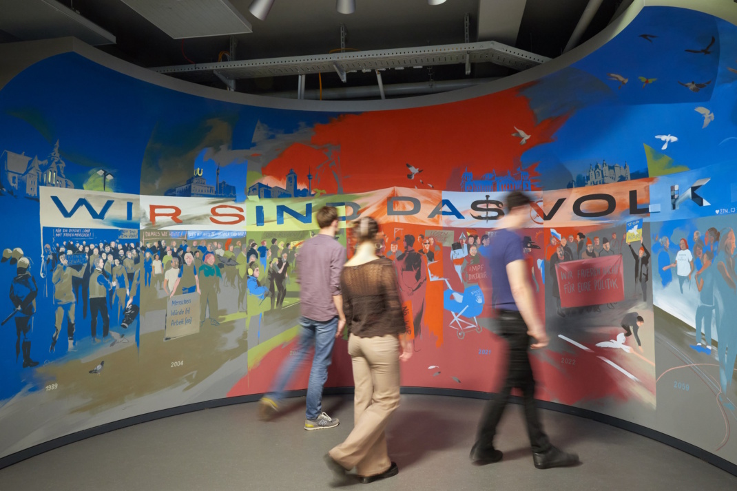Besucher vor Wandbild in der Ausstellung.
