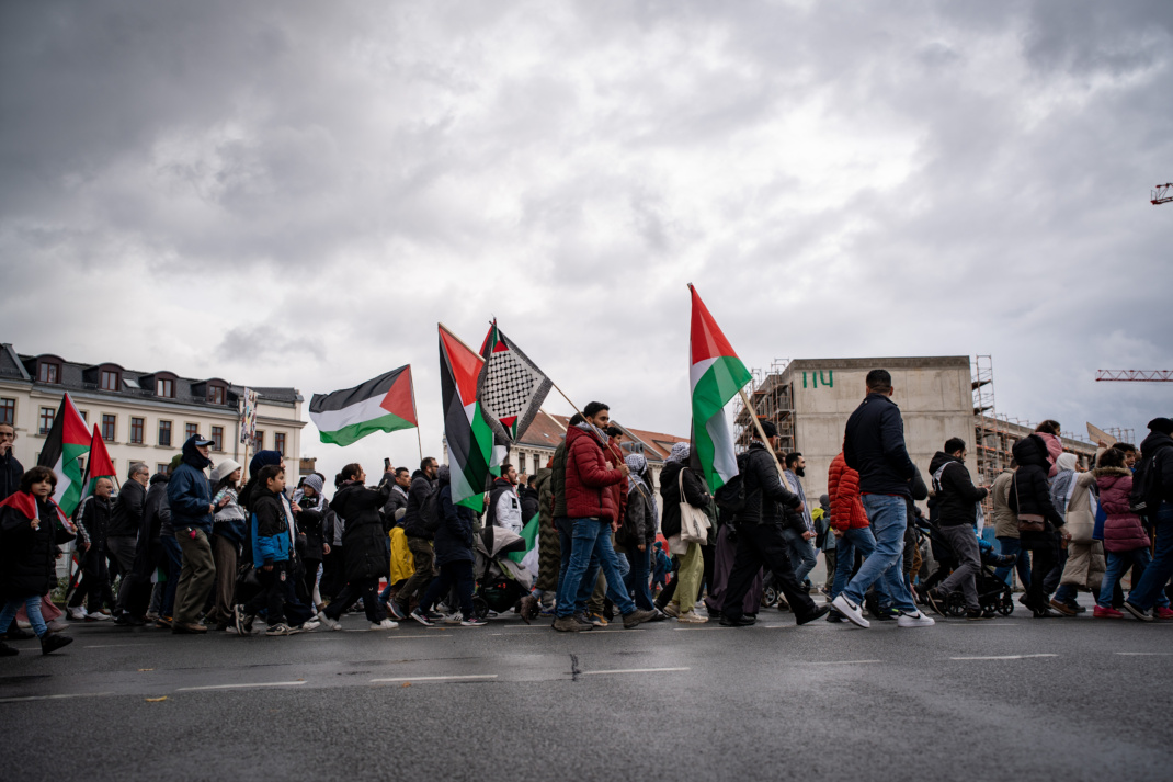 Menschen auf Demo mit Palästina-Flagge.