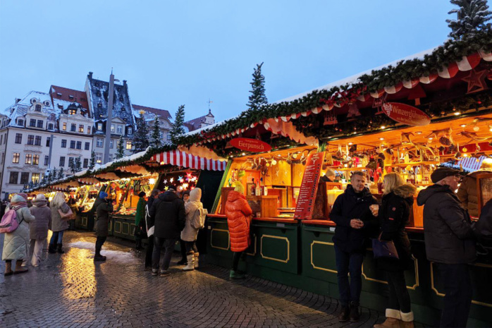 Marktstände, bunt erleuchtet, davor Menschen
