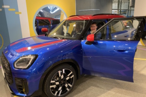 Mann sitzt in blau-rotem Wagen bei geöffneten Türen.
