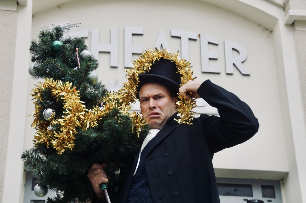 Mann mit Gut vor Hausfassade.