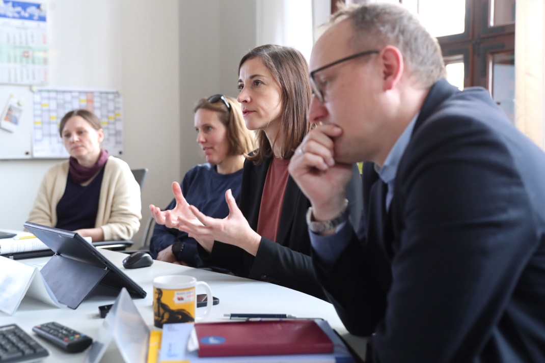 Mehrere Personen sitzen nebeneinander, Seitwnaufnahme.