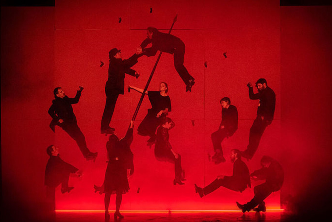 Dunkle Silhouetten vor rotem Hintergrund.