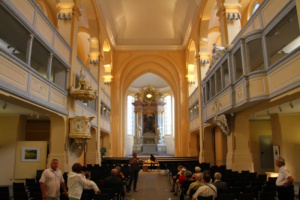 Kirchenraum und gefüllte Besucherbänke.