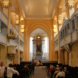 Kirchenraum und gefüllte Besucherbänke.