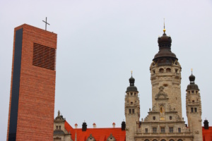 Kirchturm mit Kreuz und Rathaus in Leipzig.