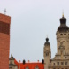 Kirchturm mit Kreuz und Rathaus in Leipzig.