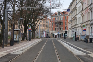Straße in der Stadt mit Haltestellenbereich und Schienen.