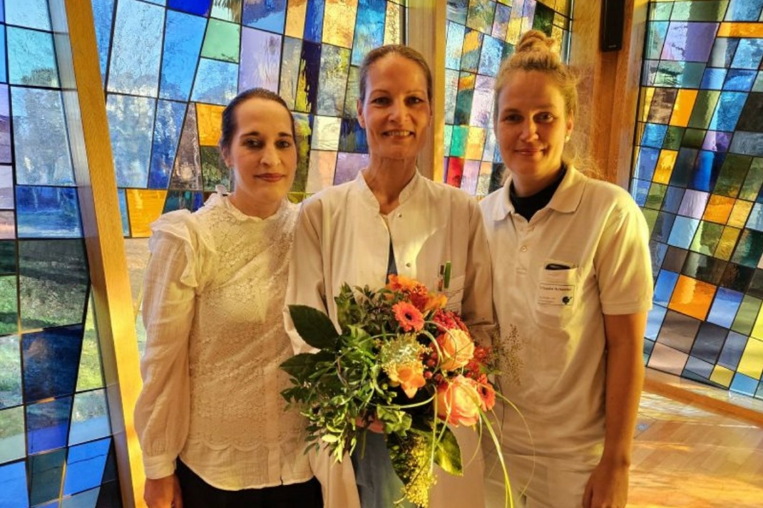 Oberärztin Dr. Anja Mende (Bildmitte) mit Blumenstrauß zum Jubiläum und ihrem palliativmedizinischen „Kernteam“, zu dem die pflegerischen Fachkräfte Theresa Hirschel (links) und Claudia Hofstetter gehören. Foto: Alexander Friebel