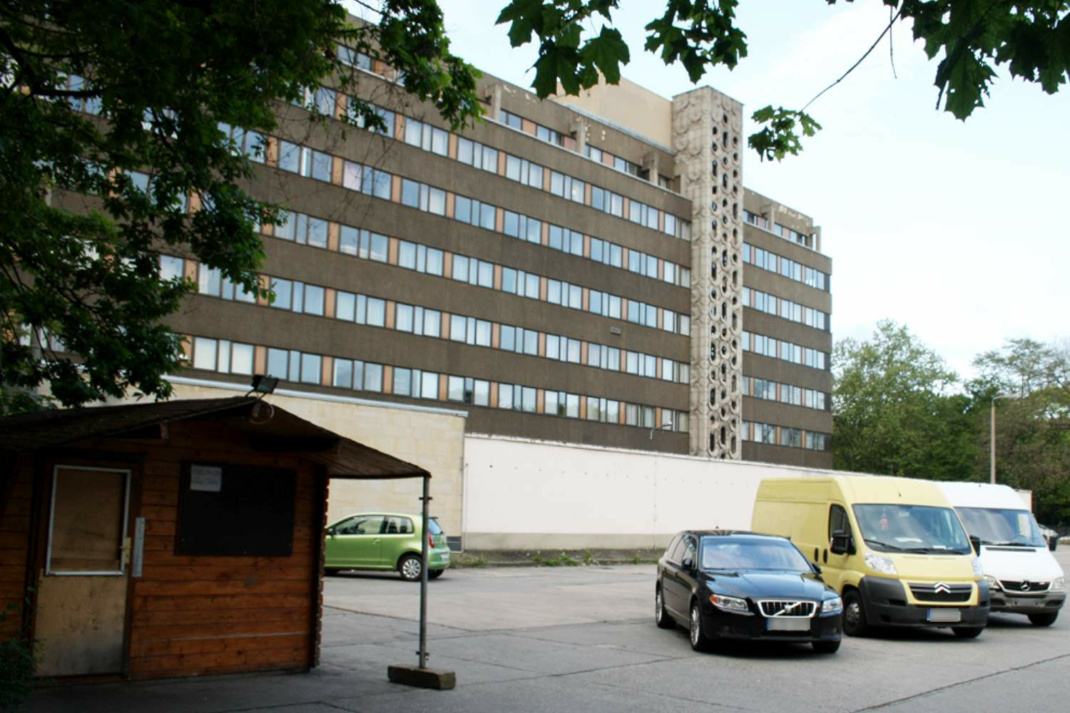 Parkplatz, stehende Autos, Parkhäuschen, Gebäudekomplex.