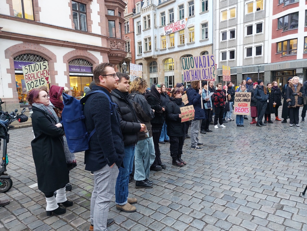 Menschen stehen zum Protest auf einem Platz.