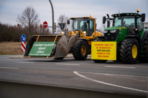 Traktoren mit Protestschildern blockieren eine Autobahnzufahrt.
