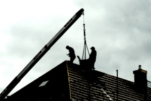 Arbeiter auf einem Dach, schattenhafte Darstellung.