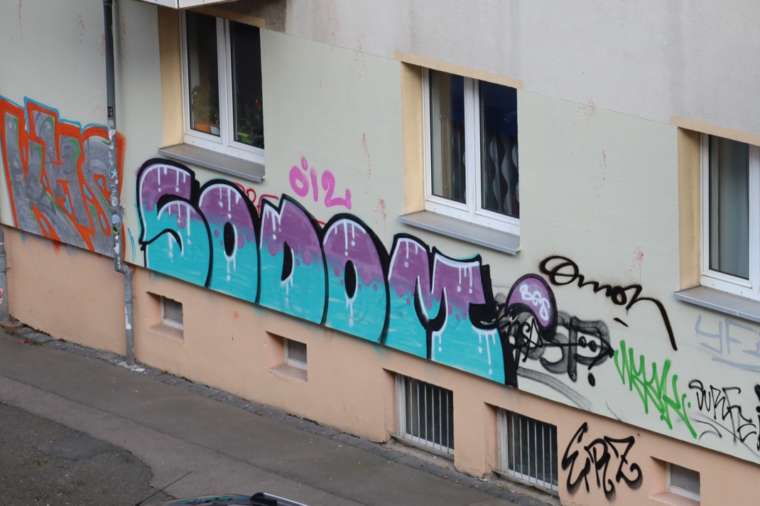 Helle Hauswand mit Graffiti.