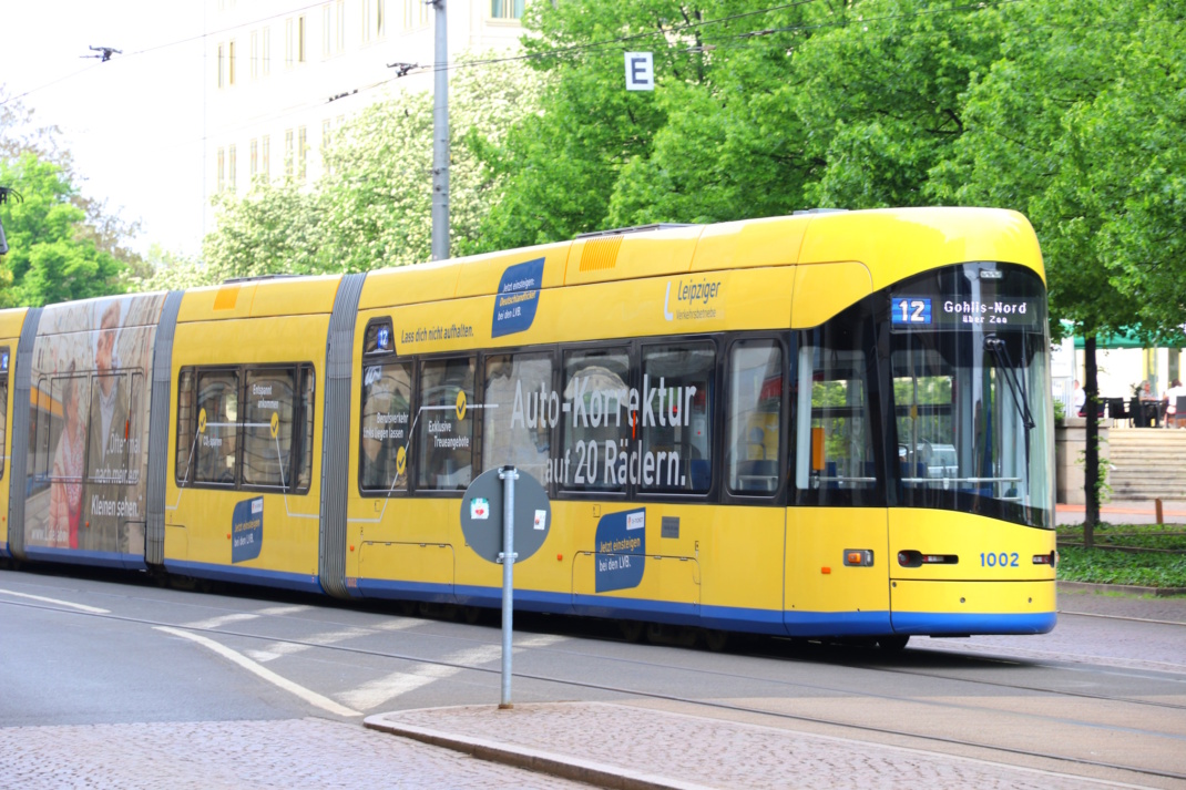 Gelb lackierte Straßenbahn unterwegs.