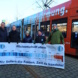 Straßenbahn und Personen mit Plakat.
