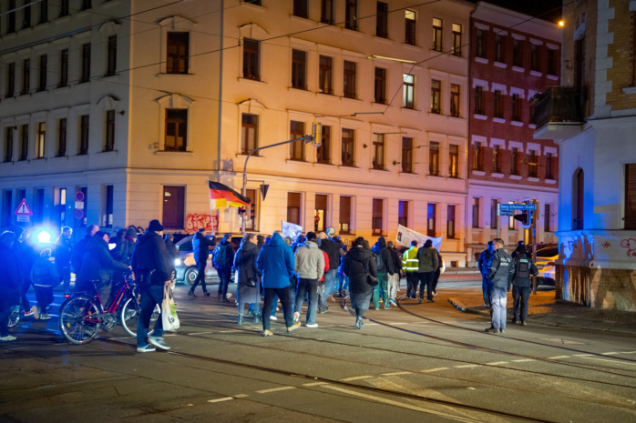 Menschenmenge vor einem Wohnhaus. Dabei eine Deutschlandflagge