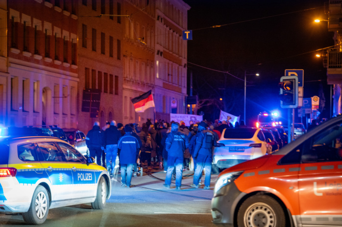Menschen mit Deutschlandflagge, im Vorderung Polizeiautos