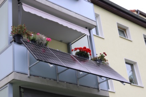 Balkon an Mehrfamilienhaus mit Blumenkästen und Solaranlage.