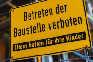 Verbotsschild zum Betreten einer Baustelle, schwarze Schrift und gelber Untergrund.