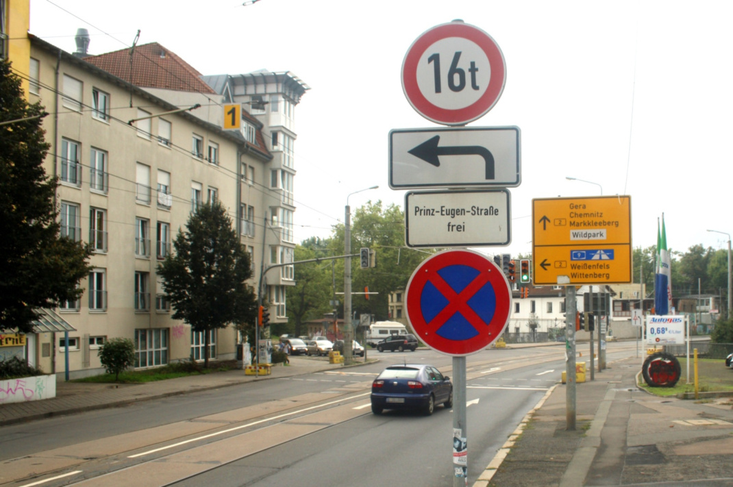 Befahrene Fahrbahn, Wohnhäuser, Verkehrsschilder.