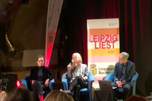 Pressekonferenz, Podium, drei Personen auf einer Bühne.