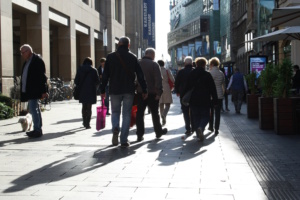 Einkaufsstraße mit Menschen, Sonnenlicht.