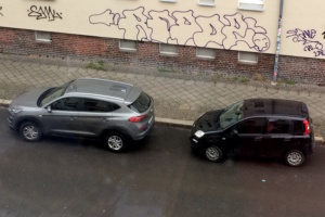 Zwei parkende Autos am Straßenrand, Aufnahme von oben.