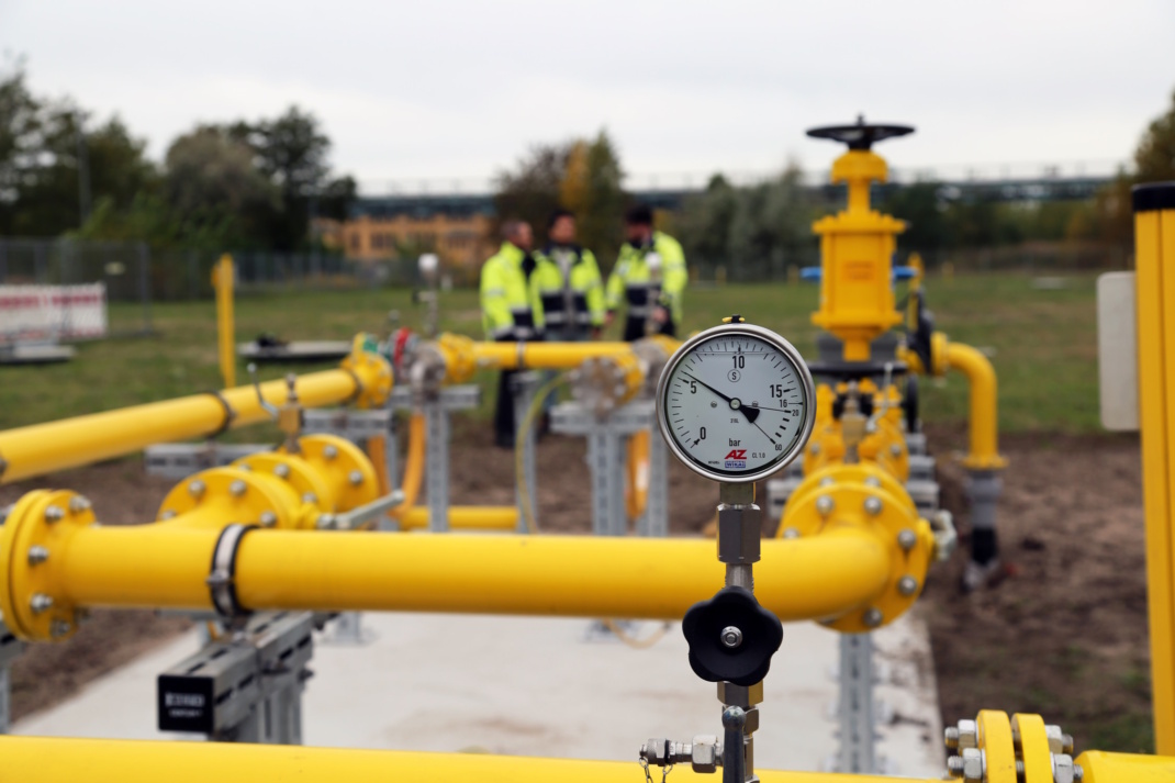 Gelbe Leitung mit Zähler, Personen im Hintergrund.