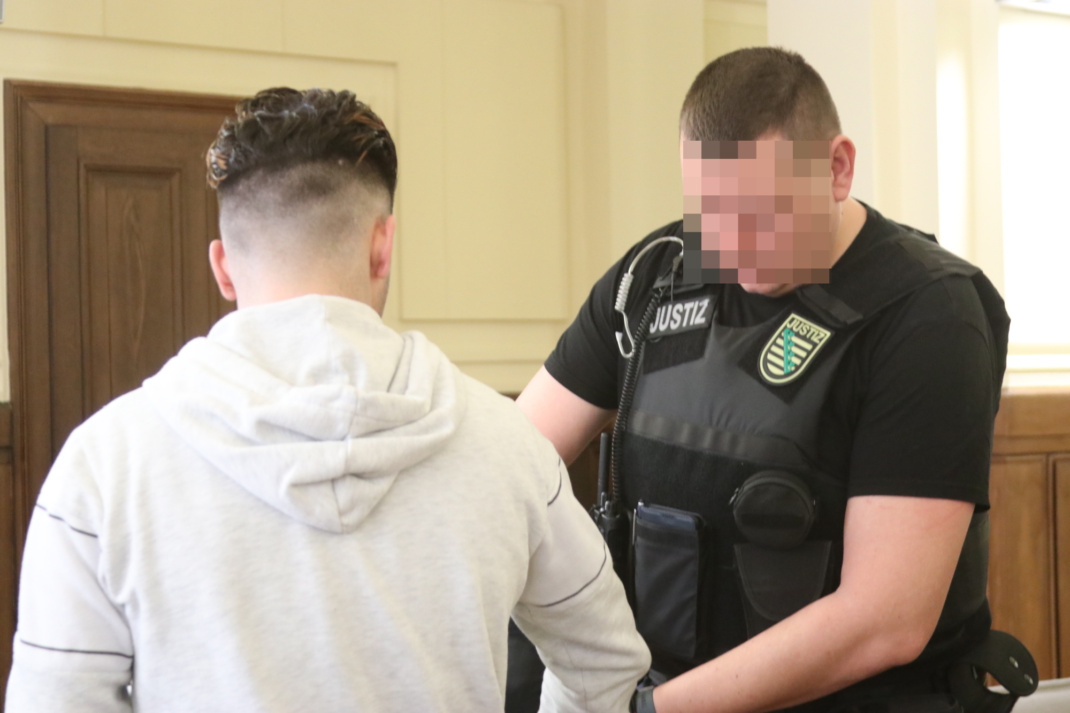 angeklagtem werden vom Wachtmeister Handschellen abgenommen.